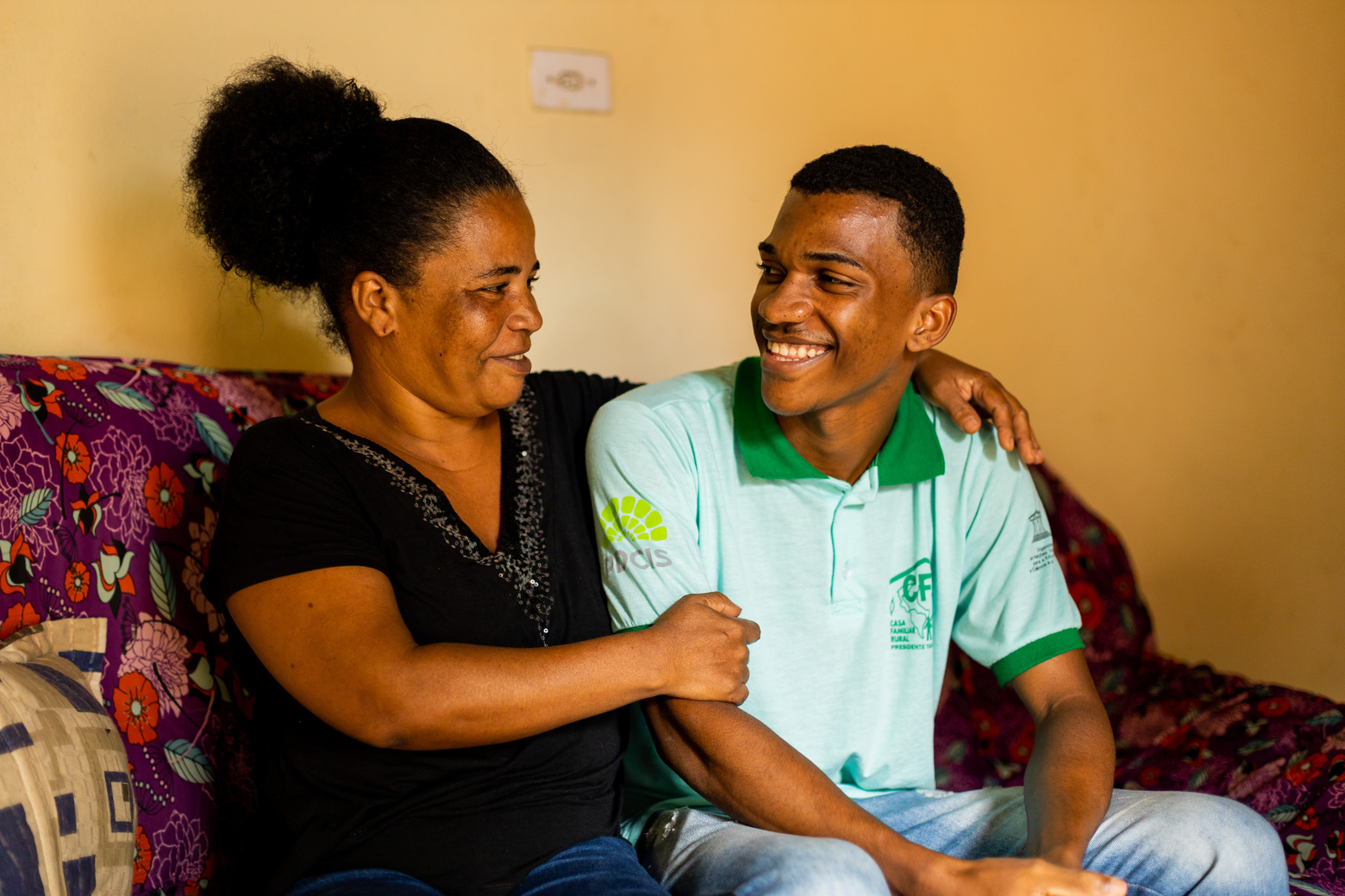 Um jovem sorri com sua mãe na sala de sua casa